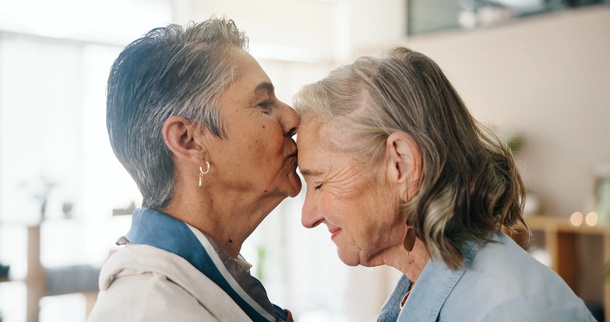 Older woman kissing her partner on the forehead at home