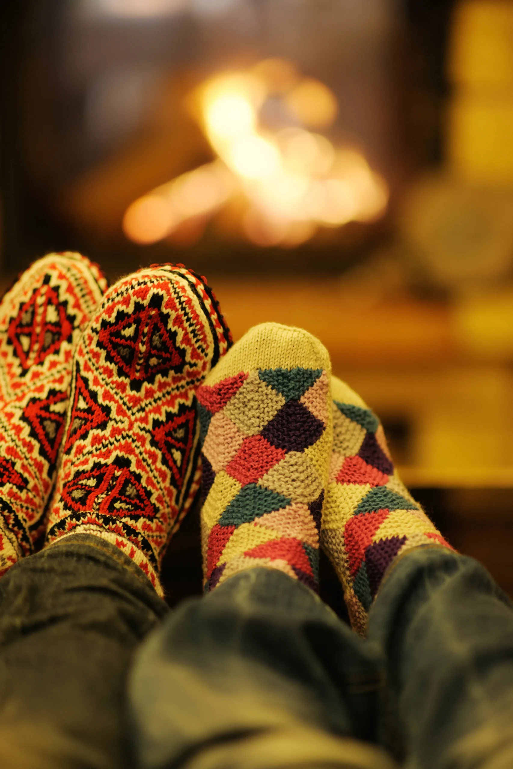 Colorful patterned socks warming by a fireplace