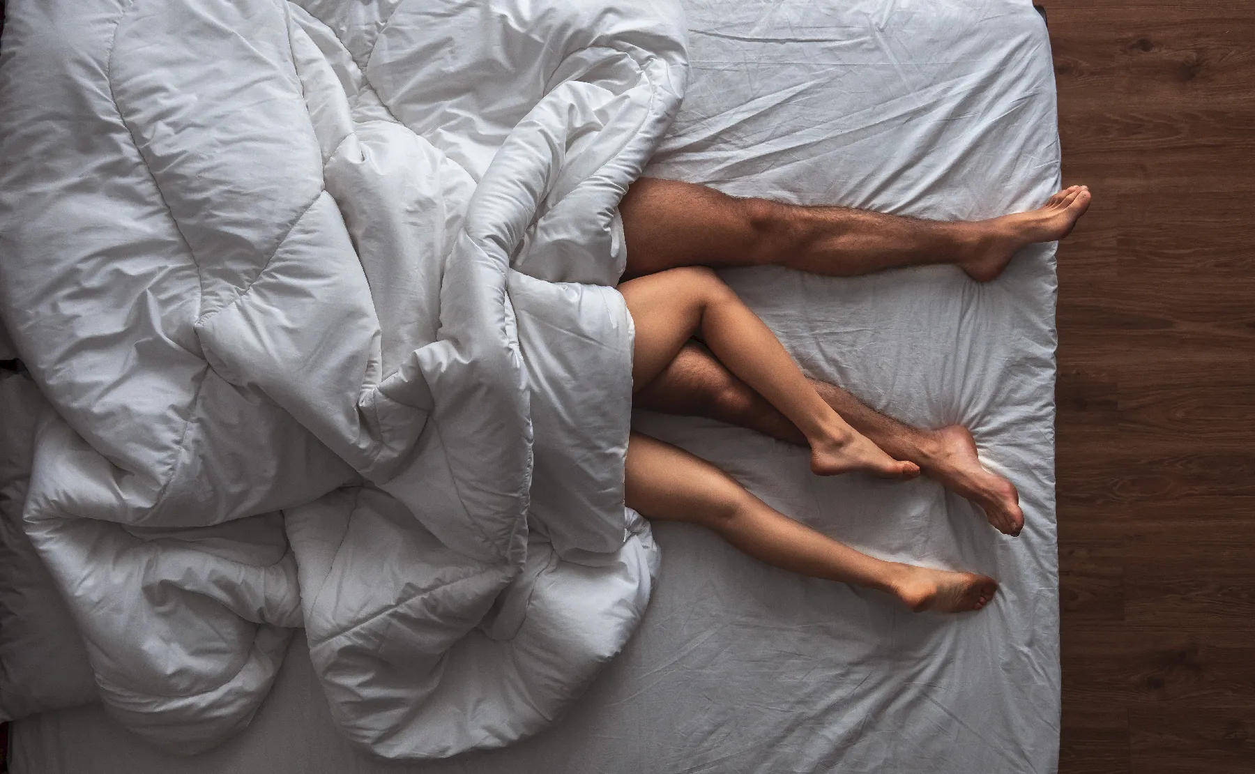 Couple relaxing together under a white duvet