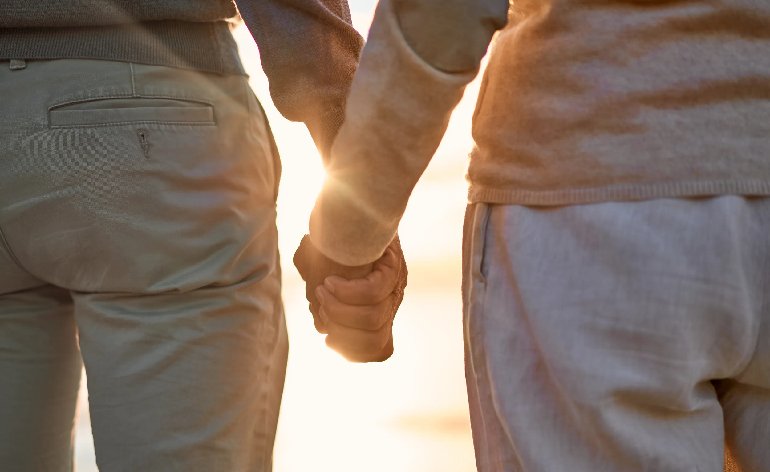 Couple holding hands while walking outdoors at sunset